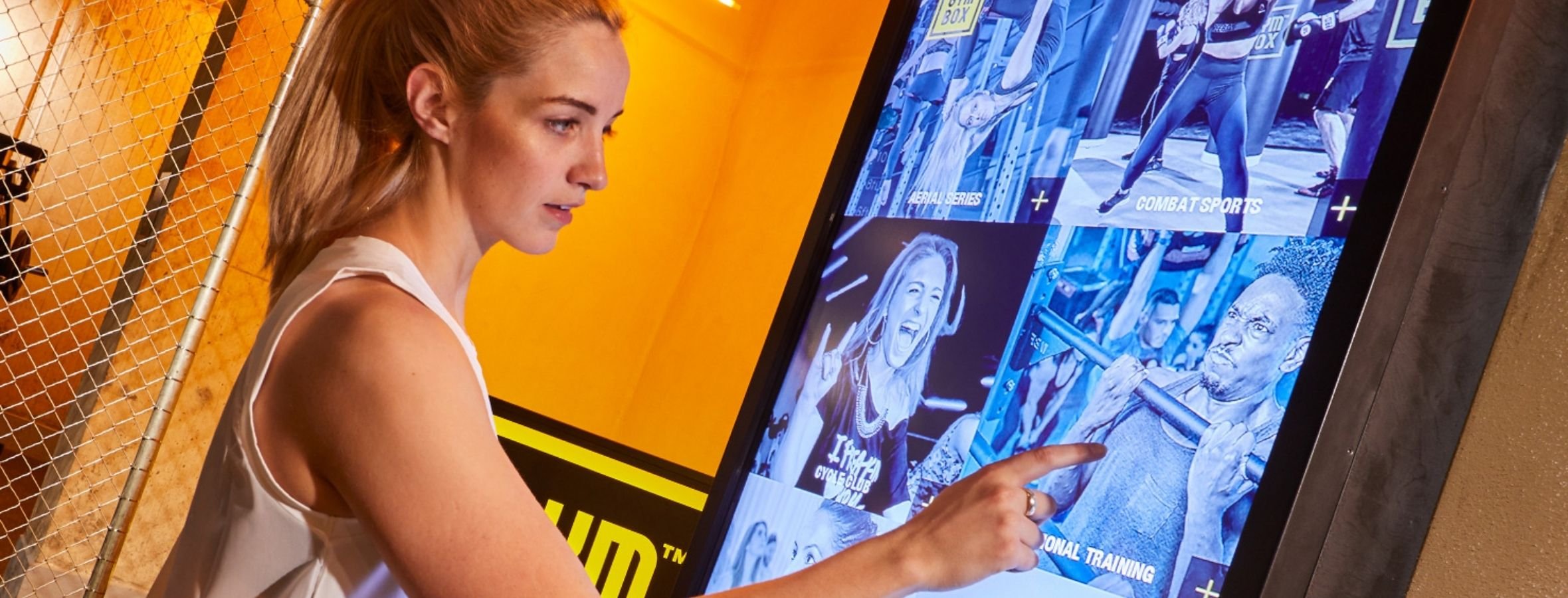 A woman selecting a virtual class from an on demand touchscreen TV