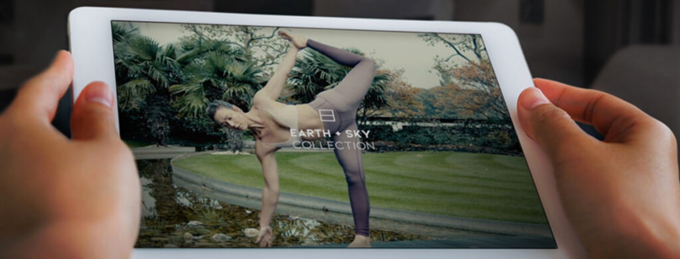 A tablet showing a virtual fitness app with a woman holding a yoga pose