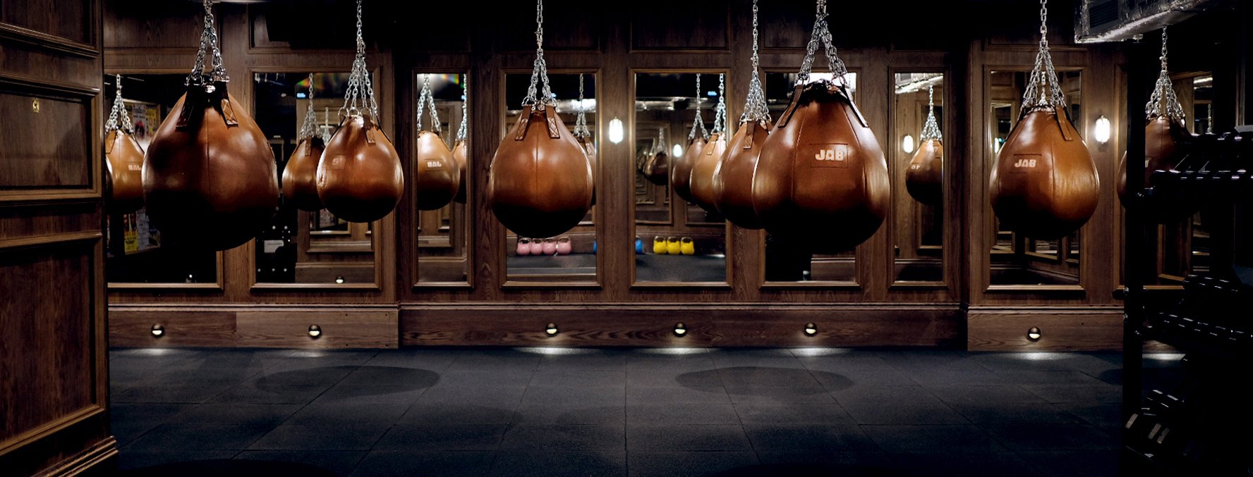 JAB Boxing's wood clad and mirrored boxing studio with brown leather punch bags hanging from the ceiling