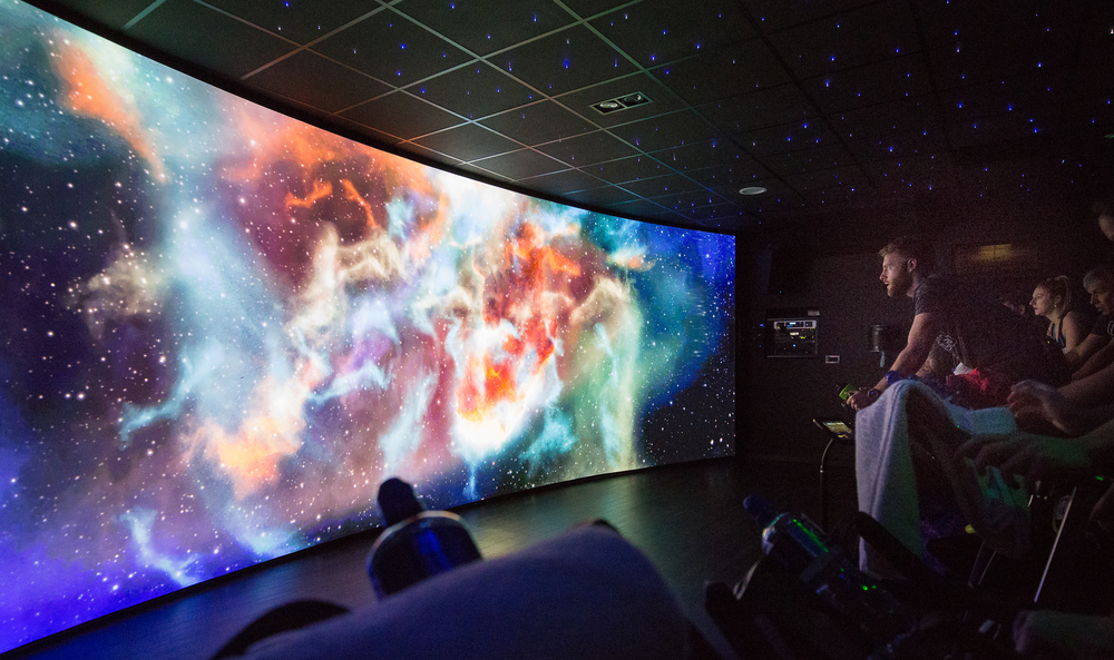An immersive spin studio using a wrap around projection wall showing a space scape 